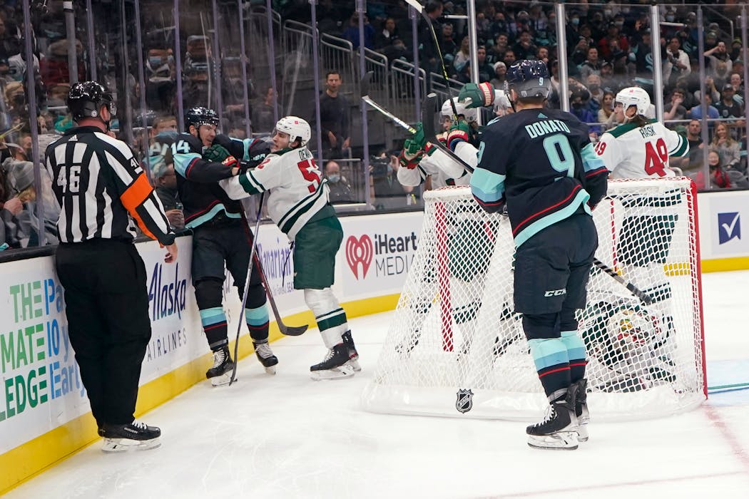 Winger Connor Dewar (52), playing in his first NHL game with the Wild, mixed it up behind the net with Kraken winger Nathan Bastian in the first period Thursday night. 