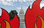 In this Oct. 15, 2021, photo, the U.S. Capitol is seen between cardboard cutouts of flames during a climate change protest near the U.S. Capitol in Wa
