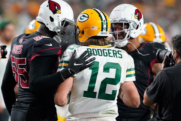Green Bay Packers quarterback Aaron Rodgers (12) is greeted by Arizona Cardinals' Chandler Jones (55) and  Isaiah Simmons (9) after an NFL football g
