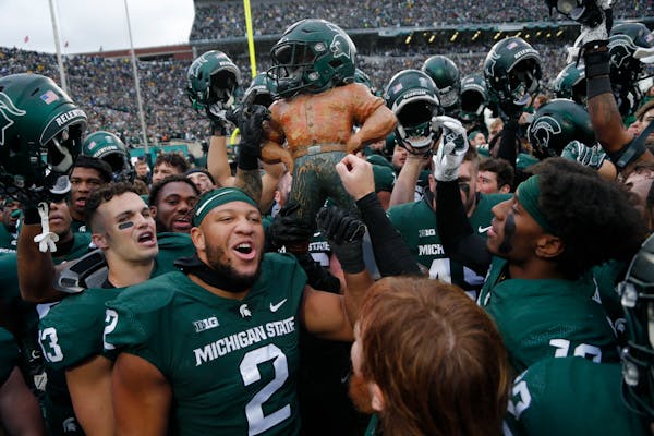 Michigan State players celebrated with the Paul Bunyan trophy after defeating Michigan last Saturday in East Lansing.