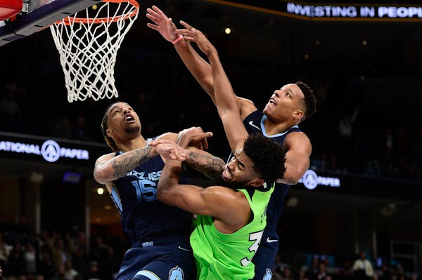Karl-Anthony Towns of the Wolves battled for position against Grizzlies Brandon Clarke (15) and Desmond Bane in overtime Monday night.