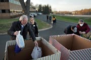 Kevin Lytle, left, the community and business engagement manager of PRISM, helps load gifts into the large drop boxes outside the Minneapolis Regional