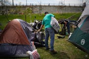 Chris Knutson, an outreach worker with St. Stephens Human Services, handed a blanket to resident of the encampment near the Sabo bridge in Minneapolis