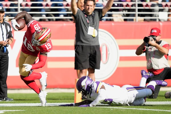 The 49ers’ Deebo Samuel (19) scores a touchdown past Minnesota Vikings free safety Xavier Woods on Sunday.