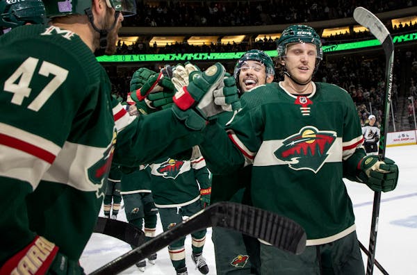 Matt Dumba (24) and Jonas Brodin (25) of the Minnesota Wild celebrate a Brodin goal with the bench in the second period Tuesday, Nov. 30, 2021 at Xcel