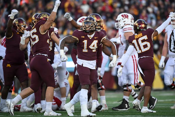 Gophers defensive players, including linebacker Braelen Oliver (14), celebrated a third-down stop in their 23-13 win over Wisconsin on Nov. 27.