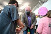 Gov. Tim Walz hands challenge coins to Jackson, 9, and Makenna Spiekermeier, 5, after they received a dose of a COVID-19 vaccine Thursday at Century C