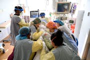 Respiratory therapist Spirya Andrews, back center, works with critical care nurses and assistants to rotate a critically-ill COVID patient at North Me