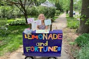Willa reveals fortunes on the other side of colorful art she hangs above her lemonade stand. Minneapolis lemonade seller, 7, adds artful fortune-telli