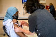 M Health Fairview nurse Terry Tran administers a COVID-19 booster shot into the arm of Mona Abdullahi, 28, Friday, Dec. 3, 2021 at the Brian Coyle Cen
