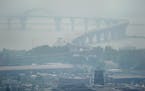 As the Greenwood Fire continues to burn, smoke from the blaze fills the air, almost obscuring the Bong Bridge and Denfeld Senior High School, bottom t