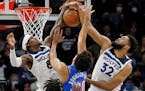 Oklahoma City center Jeremiah Robinson-Earl tries to go to the basket as Timberwolves forward Jarred Vanderbilt and center Karl-Anthony Towns defend i
