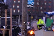 A person builds a fire Tuesday, Jan. 11, 2022 at a near Northside homeless encampment under an eviction notice in Minneapolis, Minn. ] DAVID JOLES •
