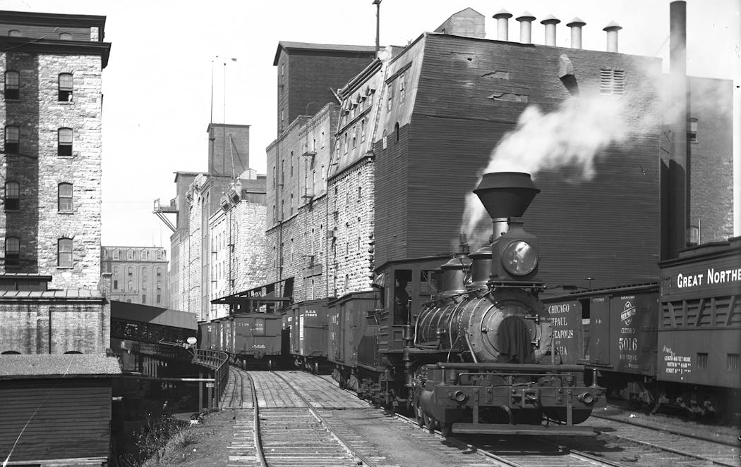 A switching train travels behind several mills in the Mill District in 1897.