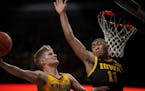 Hawkeyes guard Tony Perkins, right, put pressure on Gophers guard Luke Loewe at the basket during the first half Sunday at Williams Arena. 