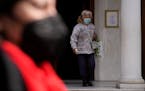 A woman wearing a face mask to curb the spread of coronavirus, exits from a Greek Orthodox church in Athens, Greece, Monday, Jan. 17, 2022. 