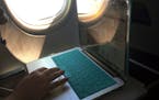 FILE - A passenger uses a laptop aboard a commercial airline flight from Boston to Atlanta on July 1, 2017. The airline industry is raising the stakes