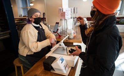 Mariam Kayali, right, had to show her COVID-19 vaccination card to server Aliya Hinz to dine in at the Hark Cafe downtown in Minneapolis on Wednesday.