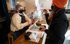 Mariam Kayali, right, had to show her Covid-19 vaccination card to server Aliya Hinz to dine in at the Hark Cafe downtown in Minneapolis, Minn., on We