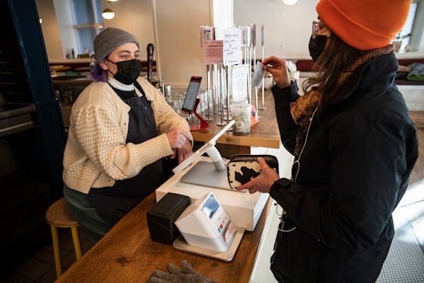 Mariam Kayali, right, had to show her COVID-19 vaccination card to server Aliya Hinz to dine in at the Hark Cafe downtown in Minneapolis on Wednesday.