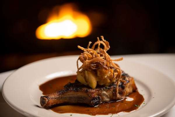 The bone-In pork chop, prepared with an herb brine, miso apple compote, and crispy onions at The Creekside Supper Club Thursday, Jan. 13, 2022 in Minn