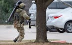 A member of the FBI runs across the parking lot while conducting SWAT operations at Congregation Beth Israel synagogue on Saturday, Jan. 15, 2022, in 