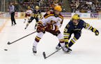 Gophers men’s hockey captain Sammy Walker battled for the puck with Michigan defenseman Ethan Edwards on Friday.