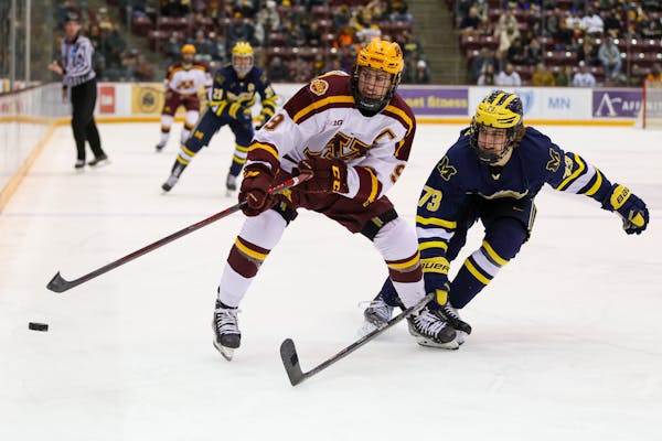 Gophers men’s hockey captain Sammy Walker battled for the puck with Michigan defenseman Ethan Edwards on Friday.