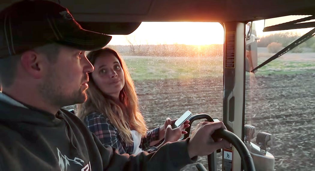In a still image from one of his videos, Zach Johnson and his wife, Becky Johnson, aka Mrs. Millennial Farmer, ride out in their tractor to watch the sunset.