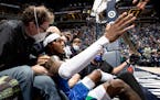 Jarred Vanderbilt (8) of the Minnesota Timberwolves is helped up a by a teammate after falling into the crowd.