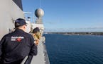 In this photo provided by the Australian Defence Force, crew on board HMAS Adelaide watch as the ship arrives in Nuku’alofa, Tonga, Wednesday, Jan. 