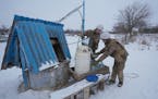 Ukrainian servicemen fill containers with water from a well for an advanced position on the front line in the Luhansk area, eastern Ukraine, Thursday,