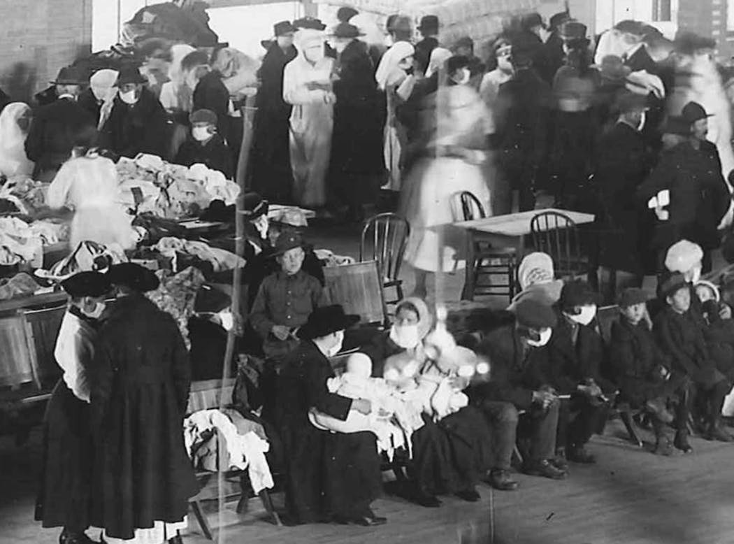 People — many of them wearing masks — attend a relief event at the Duluth Armory in 1918, following the northern Minnesota wildfires.