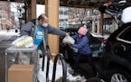 Louie Herrera, left, a volunteer with Lakeview Pantry, helps Maria Criollo load grocery items into her car outside the pantry on Jan. 24, 2022, in Chi
