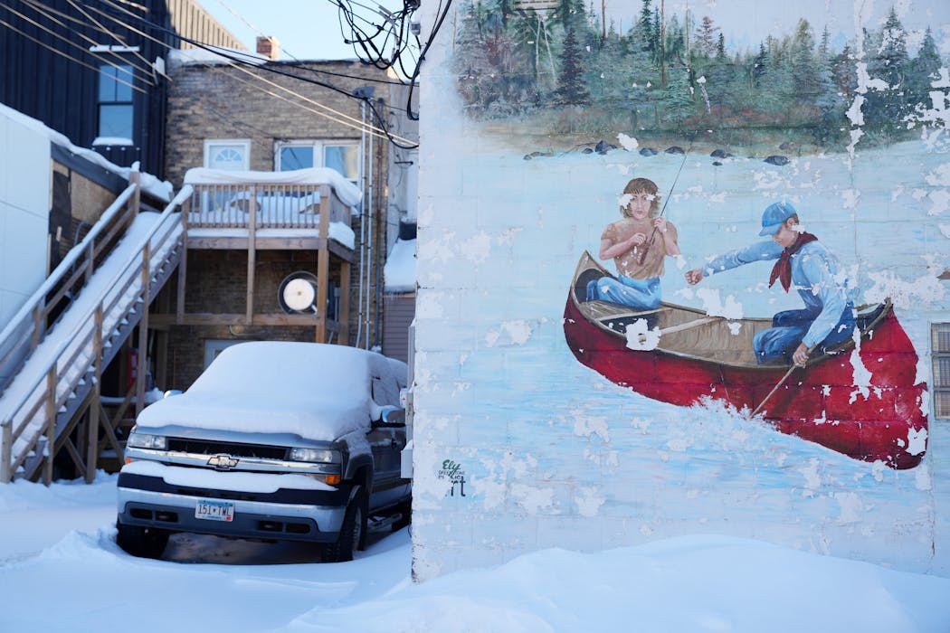 A cracked and faded mural of a couple in a canoe sits painted on the side of a building Thursday, Jan. 27, 2022 in Ely.