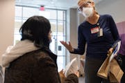 Alejandra Hernandez, 23, left, of Plymouth spoke with nurse Teresa Laing after getting a vaccine dose and a pack of KN95 masks Thursday at Hennepin Co