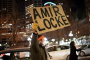 A man held a sign saying “Amir Locke” as cars lined all lanes of three blocks in downtown Minneapolis on Friday, Feb. 4, during a car caravan to p