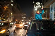 Aria Love held a Black Lives Matter sign during a car caravan through downtown Minneapolis on Friday night to protest the shooting death of Amir Locke