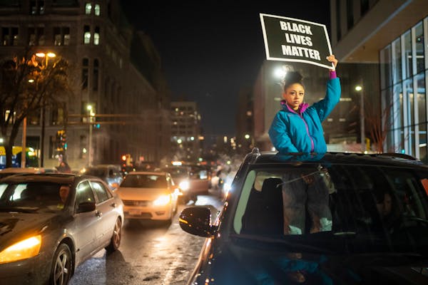 Aria Love held a Black Lives Matter sign during a car caravan through downtown Minneapolis on Friday night to protest the shooting death of Amir Locke