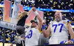 Los Angeles Rams quarterback Matthew Stafford (9) pulls up one of his daughters on stage while celebrating with offensive tackle Andrew Whitworth (77)