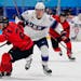Canada’s Tyler Wotherspoon (23) chases the puck with United States’ Matt Knies (67) during a preliminary round men’s hockey game at the Olympics
