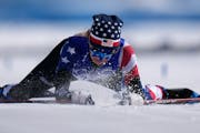 Jessie Diggins falls to the snow after crossing the finish line during the women's 30km mass start free cross-country skiing competition at the 2022 W