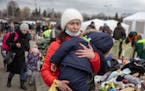 A woman carries her child as she arrives at the Medyka border crossing after fleeing from the Ukraine, in Poland, Monday, Feb. 28, 2022. The head of t