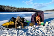 Fishing for lake trout, Dennis Anderson, left, and Pete Harris of Grand Marais peered into icy cylinders bored into thick ice on a lake off the Gunfli