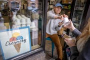 Zach Vraa hands out pints of Gotham Crunch to a line of ice cream lottery winners who were able to purchase the treat at A to Z Creamery, in Hopkins.