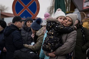 Refugees fleeing the Russian invasion of Ukraine wait for buses to transport them to their next destination after crossing the border from Ukraine in 