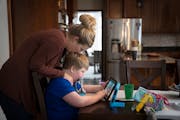Kate Swenson kisses her son Cooper as he watches Thomas the Tank Engine on his iPad at home in Woodbury. Kate Swenson has written a book called Foreve