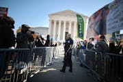 Police use metal barricades to keep protesters, demonstrators and activists apart in front of the U.S. Supreme Court as the justices hear arguments in
