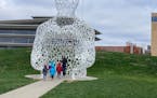 Visitors to PappaJohn Sculpture Park in Des Moines, Iowa, take a closer look at “Nomade,” a sculpture by Jaume Plensa. 