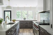 The previously dark 1970s kitchen was given a major facelift with reclaimed white oak cabinets, plank lime-washed oak floors and a glass tile backspla